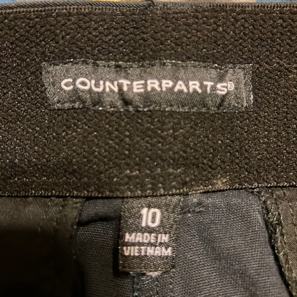 Counterparts comfortable fit a flat front, & a side button accents at hemline.
